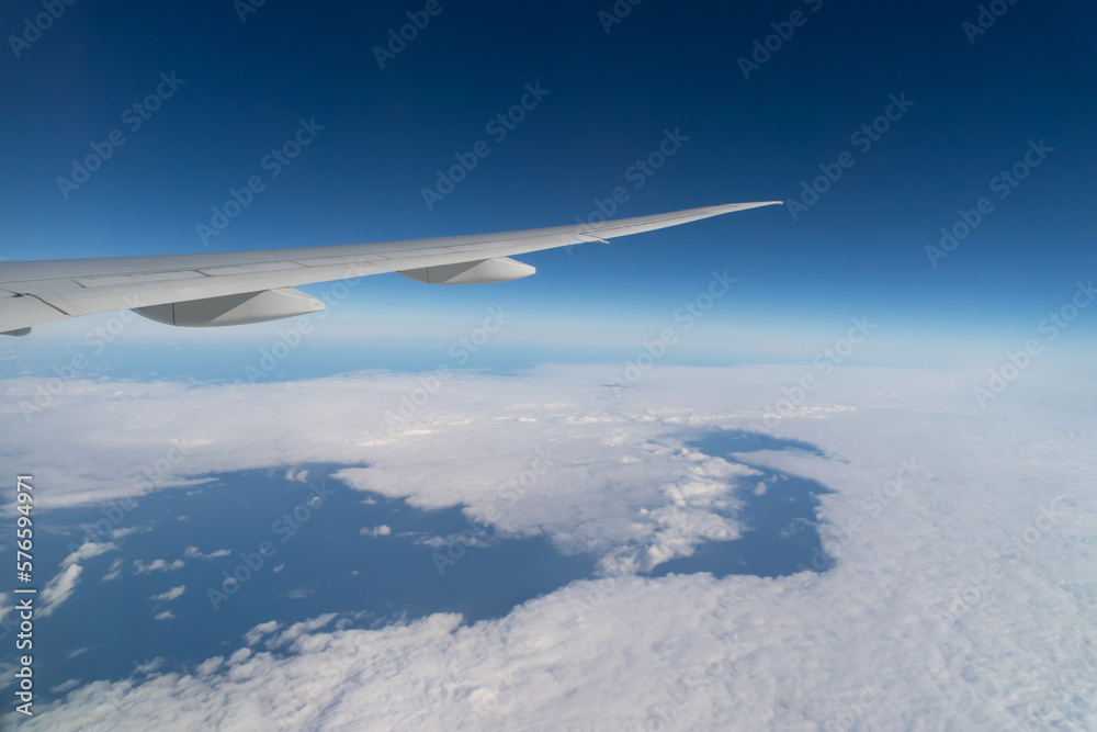 Wing of an airplane jet flying above clouds with blue sky from the window in traveling and transportation concept. Nature landscape background. Wing of an airplane jet flying above clouds with blue sky from the window in traveling and transportation concept. Nature landscape background.
