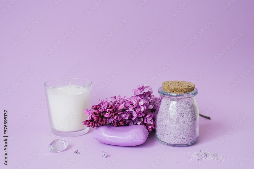 Spa setting with lilac flowers. Sea salt in a glass jar, soap and candle on the background Spa setting with lilac flowers. Sea salt in a glass jar, soap and candle on the background