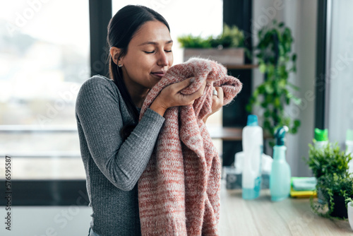 Konstfotografi Beautiful young woman holding and smelling clean clothes at home.