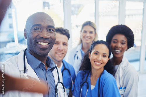 Healthcare, portrait and selfie by doctors at hospital, happy and proud, smile and bond on blurred background. Face, diversity and group pose for photo, profile picture or website homepage update