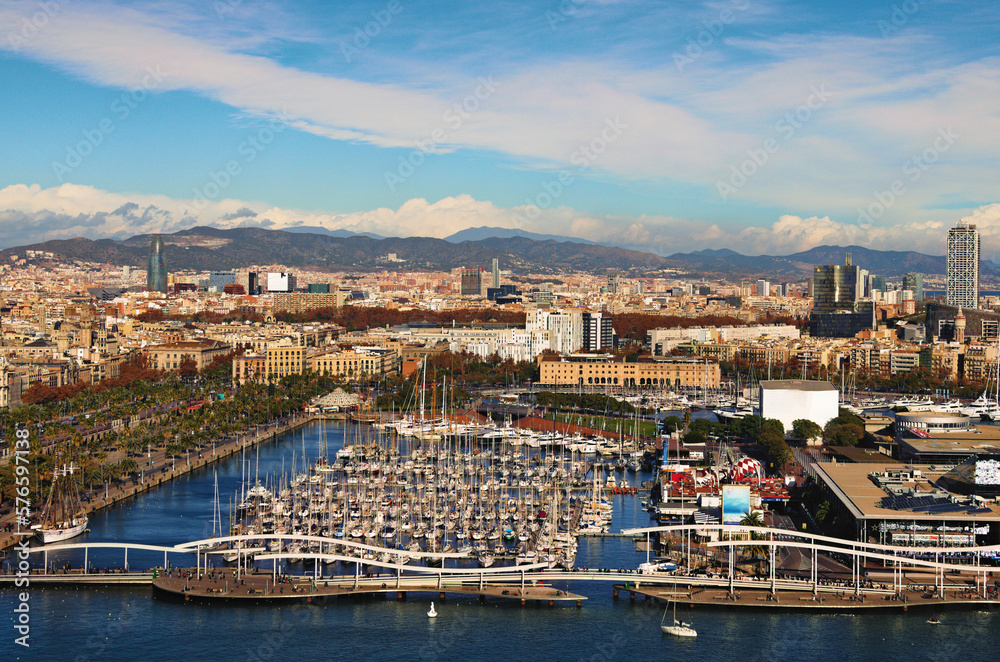 Amazing aerial landscape of historic part of Barcelona during sunny day. Embankment, harbor with moored yachts on the foreground. View from the cable car. Travel and tourism concept