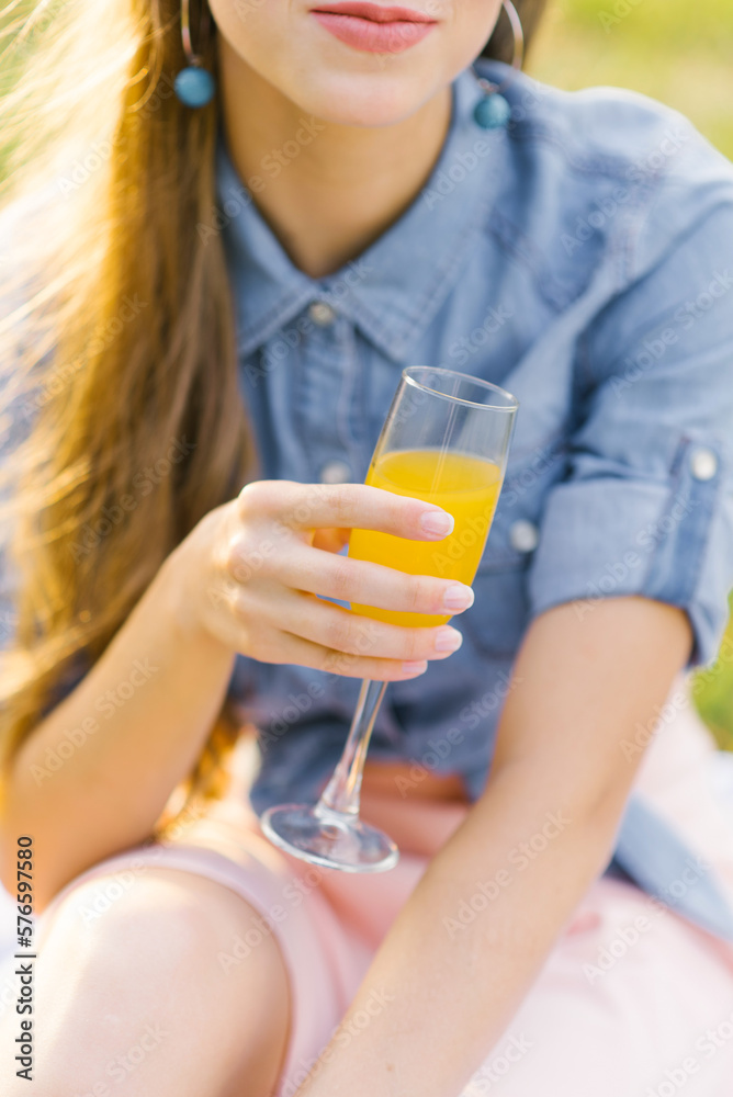 Glass of orange juice in the hand of a young woman Glass of orange juice in the hand of a young woman