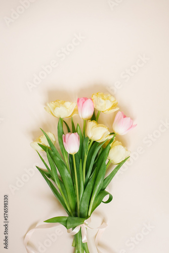 Bouquet of colorful pink and yellow tulip flowers on beige background. Spring holidays concept. Top view, flat lay, copyspace © Sunshine