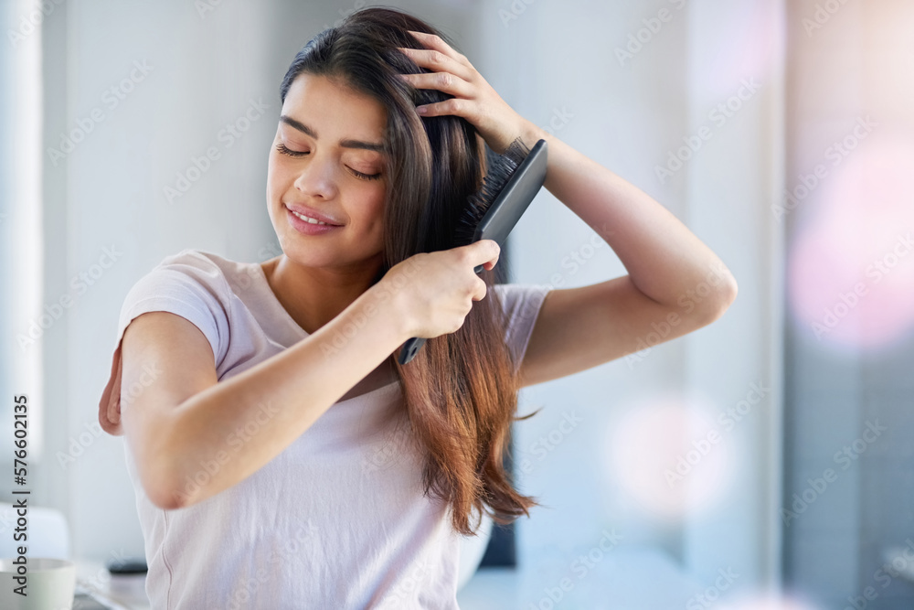 Fototapeta premium In love with her locks. Shot of a beautiful young woman brushing her hair in the bathroom at home.