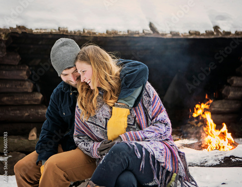 A couple share an intimate moment by a campfire on a cold winter day. photo