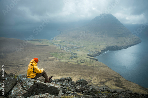 Hiker looking at view of coastline and mountain, Faroe Islands photo