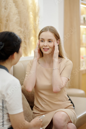 Young woman talking to her esthetician about skin problems