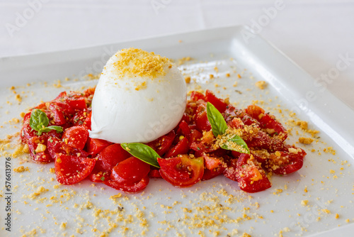 Mozzarella di bufala campana servita come antipasto con contorno di pomodori e basilico e scorza di limone in un ristorante elegante photo