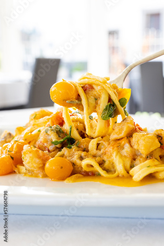 Piatto di scialatielli napoletani con pomodori datterini gialli, rana pescatrice e menta serviti come primo piatto in un ristorante elegante photo