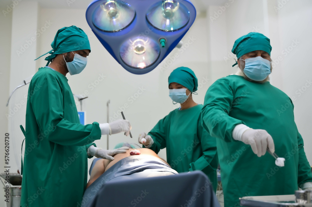 Group of surgeons and nurse in surgical green gown working at operating room of the hospital. Medical Team performing Surgical operation. Group of surgeons and nurse in surgical green gown working at operating room of the hospital. Medical Team performing Surgical operation.