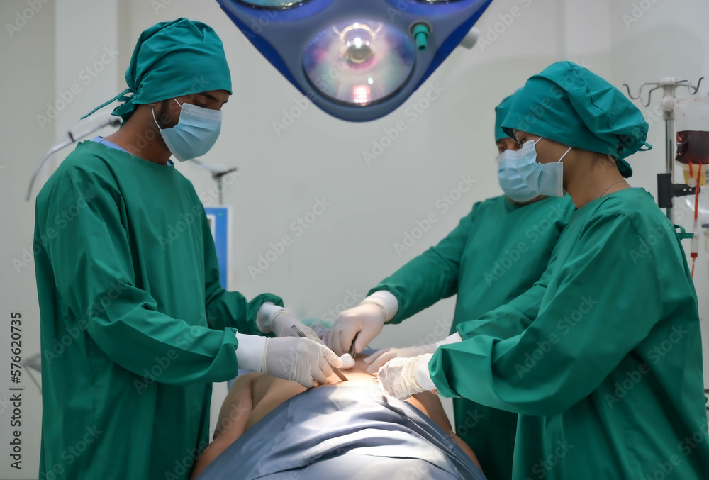Group of surgeons and nurse in surgical green gown working at operating room of the hospital. Medical Team performing Surgical operation. Group of surgeons and nurse in surgical green gown working at operating room of the hospital. Medical Team performing Surgical operation.