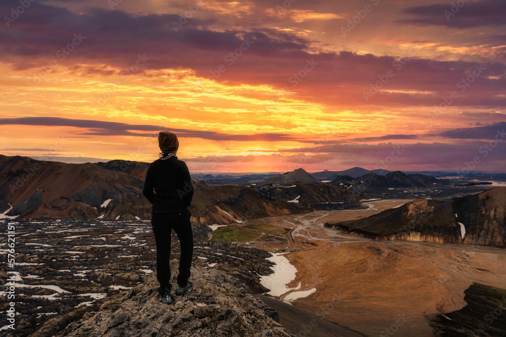 Hiker young female standing on volcanic mountain and sunset sky on summer at Icelandic Highlands