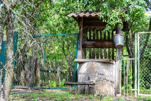 Old well with iron bucket on long forged chain for clean drinking water