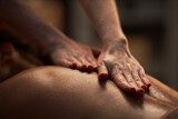 Hands of masseuse applying oil on back of young woman