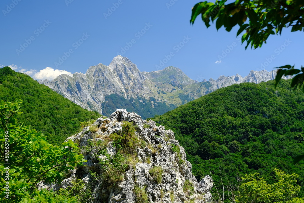 Mountains panorama. Panorama of mountains. Pizzo d'Uccello, Monte Sagro and the Apuan Alps between green woods and blue sky. Apuan Alps, Tuscany, Italy. 