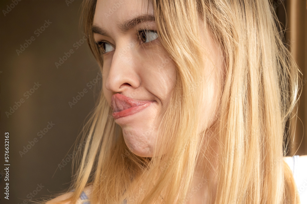 Horizontal shot of funny humorous playful young European woman sticking out her tongue, trying to touch nose with its tip. People, youth, leisure, joy, fun, spontaneous and entertainment concept. Horizontal shot of funny humorous playful young European woman sticking out her tongue, trying to touch nose with its tip. People, youth, leisure, joy, fun, spontaneous and entertainment concept.