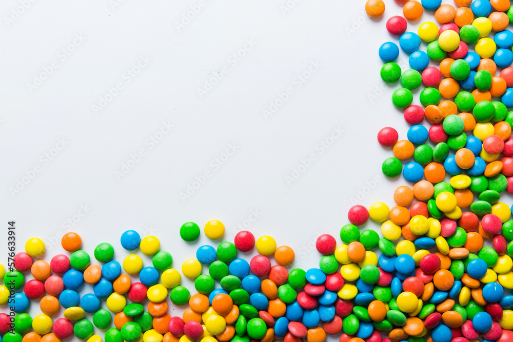 Obraz premium Mixed collection of colorful candy, on colored background. Flat lay, top view. frame of colorful chocolate coated candy