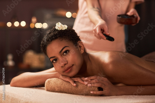 Young woman geeting stress relief hot stones massage in spa salon