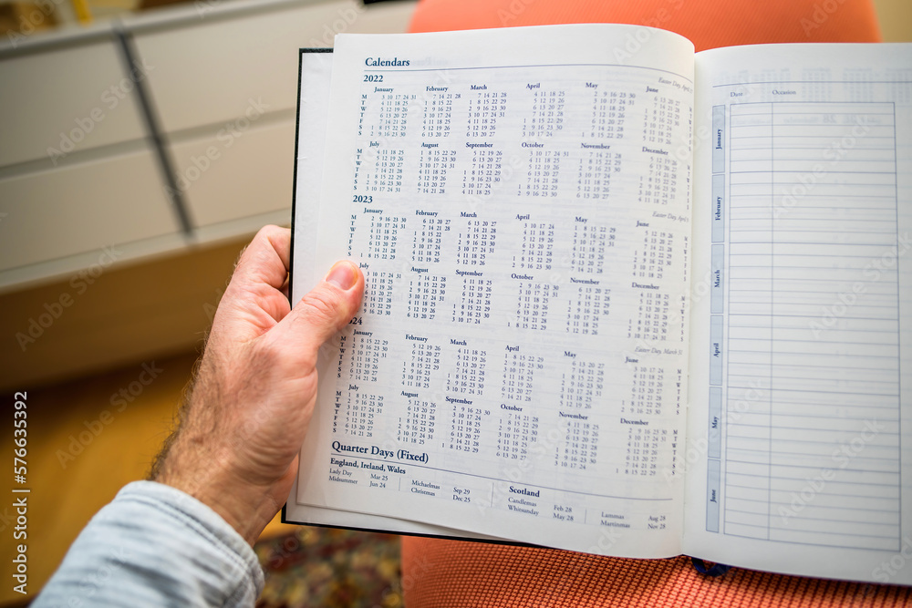 Obraz premium Male hand holding annual agenda with Calendar for 2022, 2023 and 2024 years