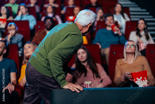 Senior man finding seat in movie theater.