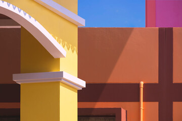 Street minimal exterior architecture background, part of yellow arch door with colorful geometric pattern of modern building walls with blue sky