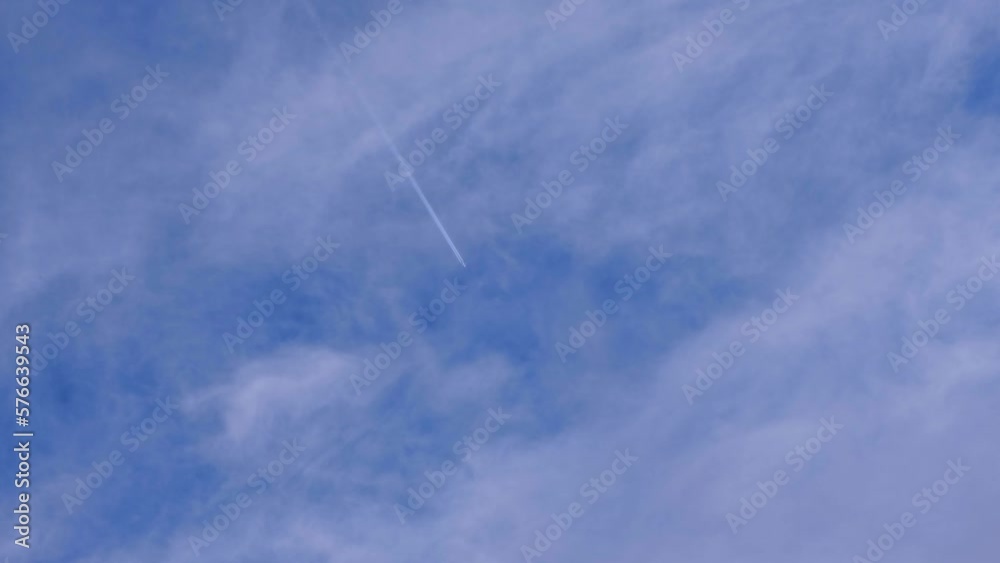 Contrails and vapor trail lines from an aeroplane aircraft flying overhead against a fine blue, slightly cloudy sky Contrails and vapor trail lines from an aeroplane aircraft flying overhead against a fine blue, slightly cloudy sky
