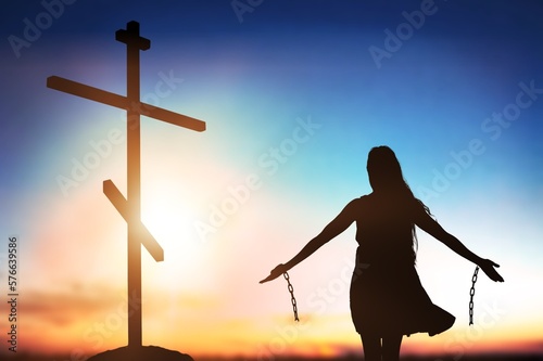 Fototapeta Silhouette of woman break chains with Holy Cross on background