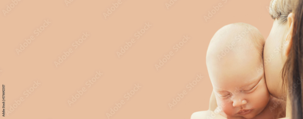 Portrait close up of baby sleeping on mother's hands on brown background, blank copy space Portrait close up of baby sleeping on mother's hands on brown background, blank copy space