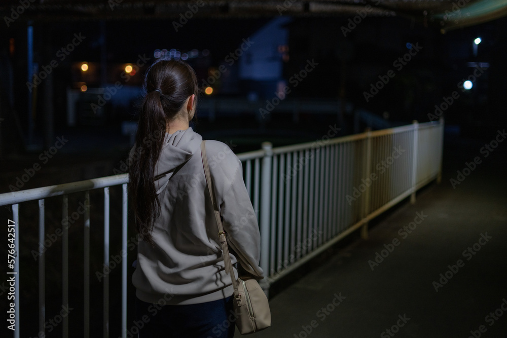 Fototapeta premium 夜道を歩く女性の後ろ姿