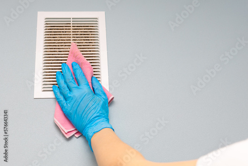 man cleaning the ventilation grill in the room.