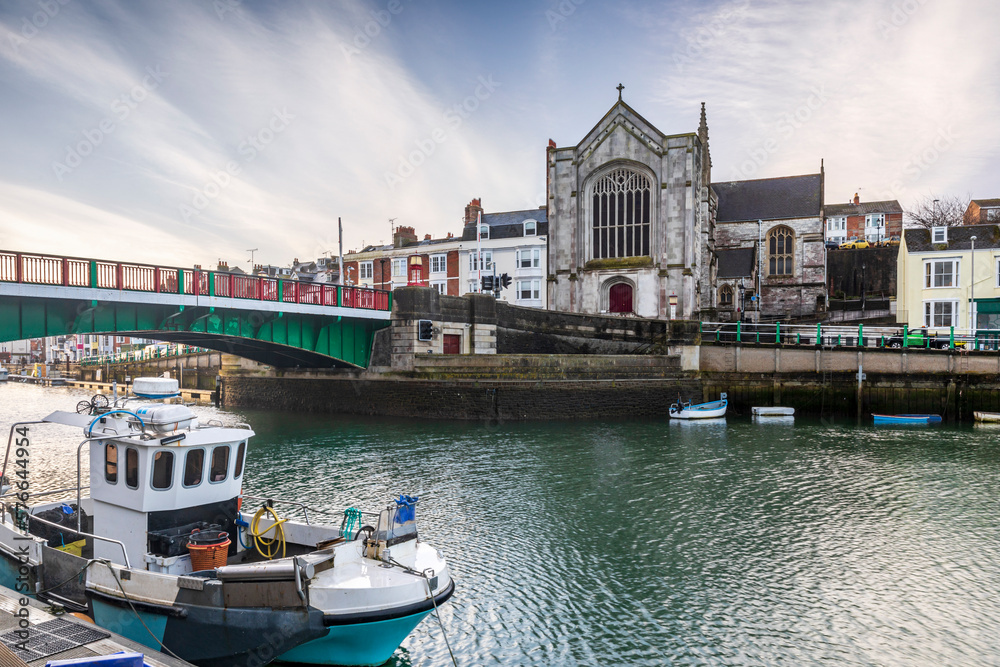 A  fishing boat moored in Weymouth Harbour in Dorset, with the Old Town Bridge and Holy Trinity Church in the background.