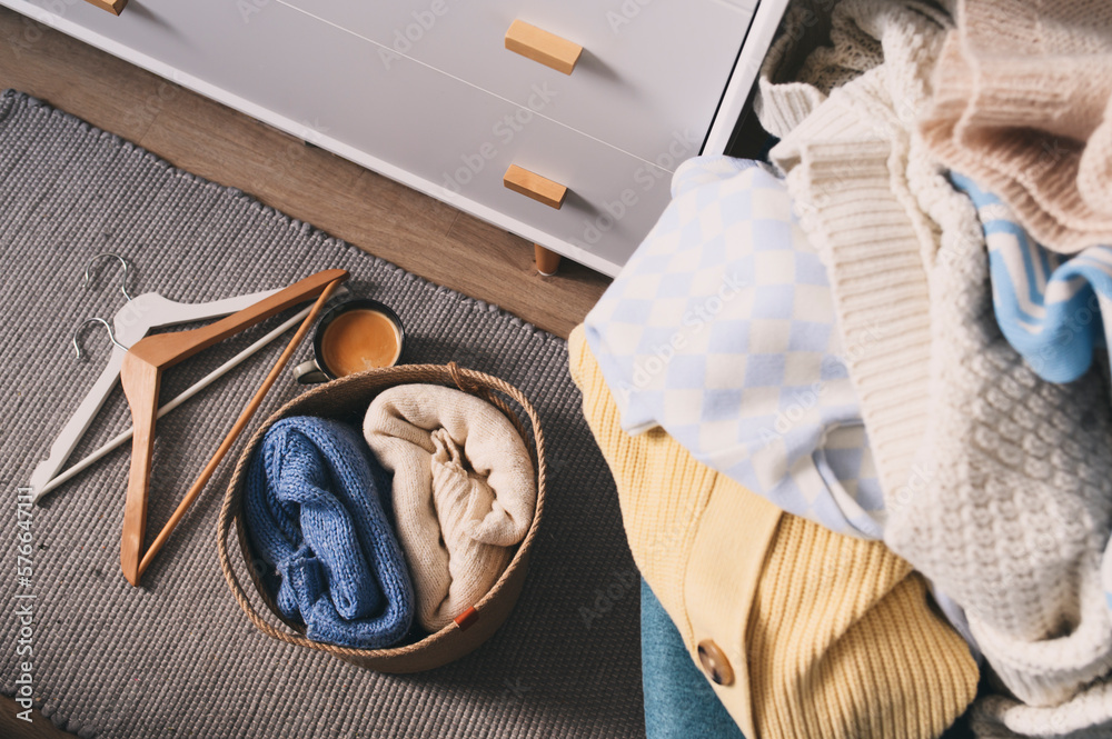 Morning home routine. Woman organizing clothes, many knitted sweaters ...