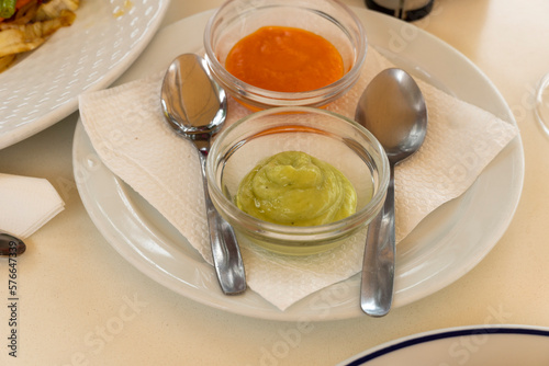 Canary Islands dish Papas Arrugadas wrinkly potatoes with Mojo picon Red hot sauce and Mojo verde Green sauce on restaurant table photo