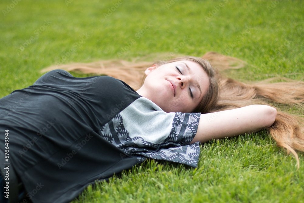 smiling happy playful young woman lying on a park lawn in summer smiling happy playful young woman lying on a park lawn in summer