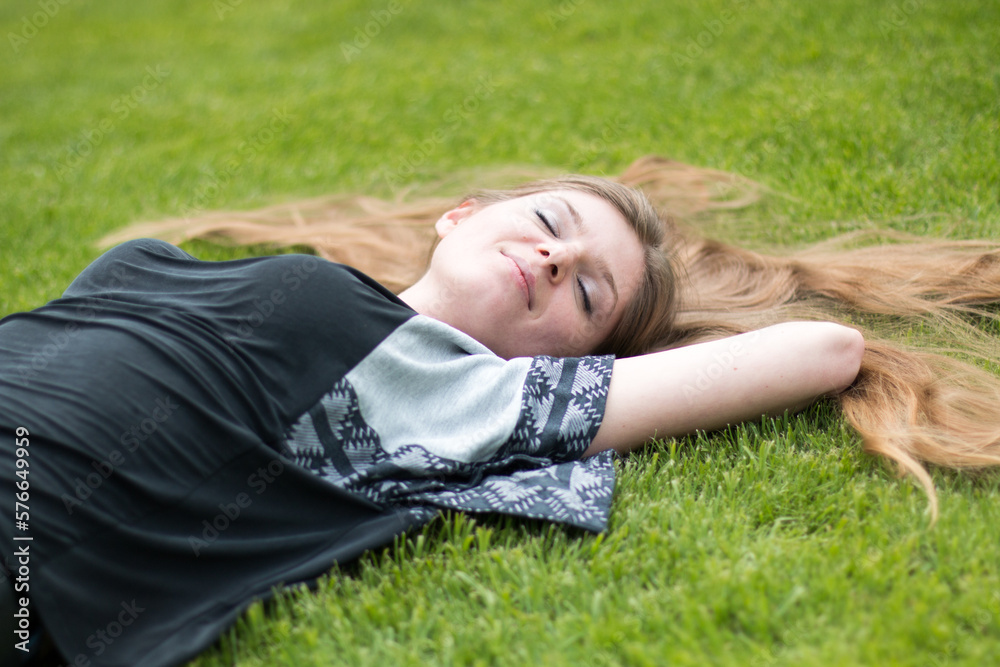 smiling happy playful young woman lying on a park lawn in summer smiling happy playful young woman lying on a park lawn in summer