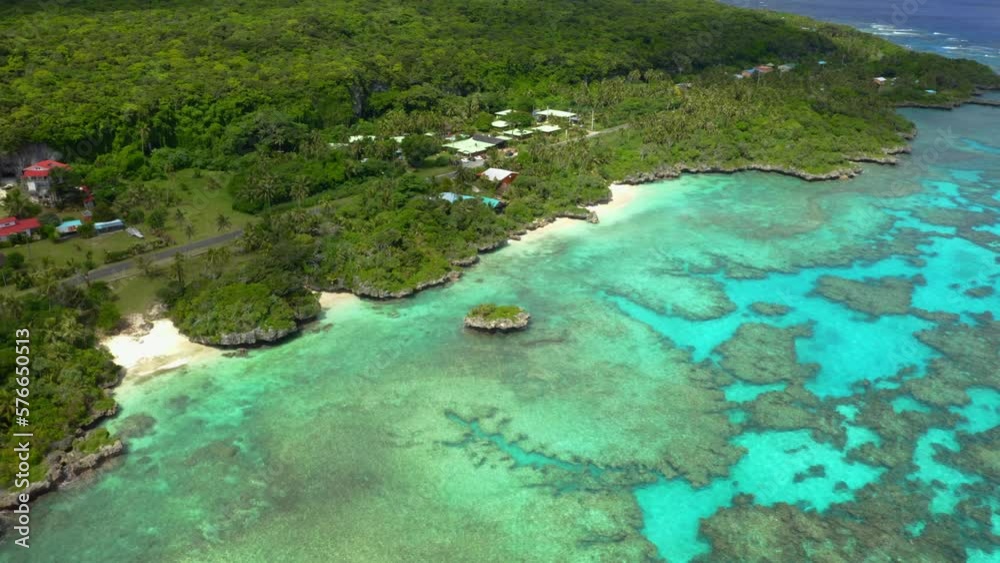 A drone captures a shot rushing towards a tropical coast, showcasing the lush green vegetation, crystal-clear waters and a little rocky island in front. A drone captures a shot rushing towards a tropical coast, showcasing the lush green vegetation, crystal-clear waters and a little rocky island in front.
