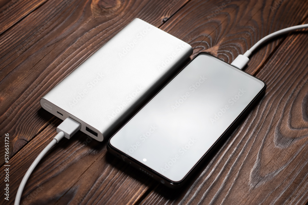 Powerbank and charge smartphone on wooden table Powerbank and charge smartphone on wooden table