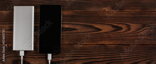 white power bank and smartphone on wooden background.