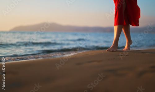 Woman in red dress walks along the beach. © M-Production