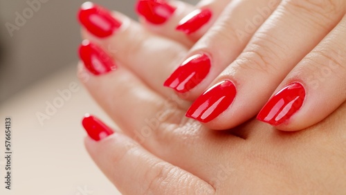 Female hands with fashionable manicure of red color . Woman shows her new red manicured nails, closeup. Beauty of nails. Classic red manicure.