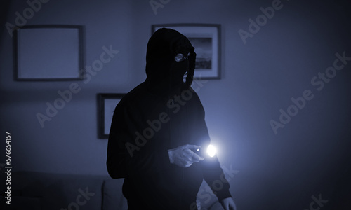Fotografiet Thief in a balaclava at night in the house.