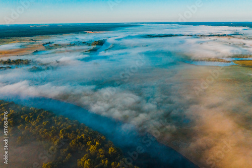 Aerial view of a beautiful summer landscape with a fog while dawn. Photo from drone of a foggy landscape in spring. Top view to land while sunrise. Early morning in nature, misty weather.