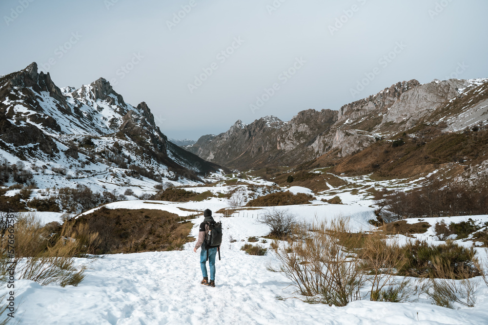 Senderista caminando por un paisaje montañoso nevado en Asturias Senderista caminando por un paisaje montañoso nevado en Asturias