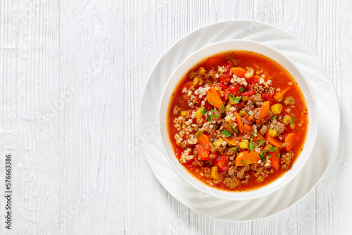 Easy hot and hearty Hamburger Soup with barley and vegetables in white bowl on white wood table