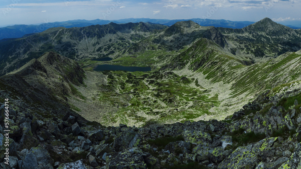 Obraz premium Panorama above the high summits of Retezat Mountains and the glacier Bucura lake beneath them. High altitude landscape with rocky mountains and alpine pastures. Carpathia, Romania.