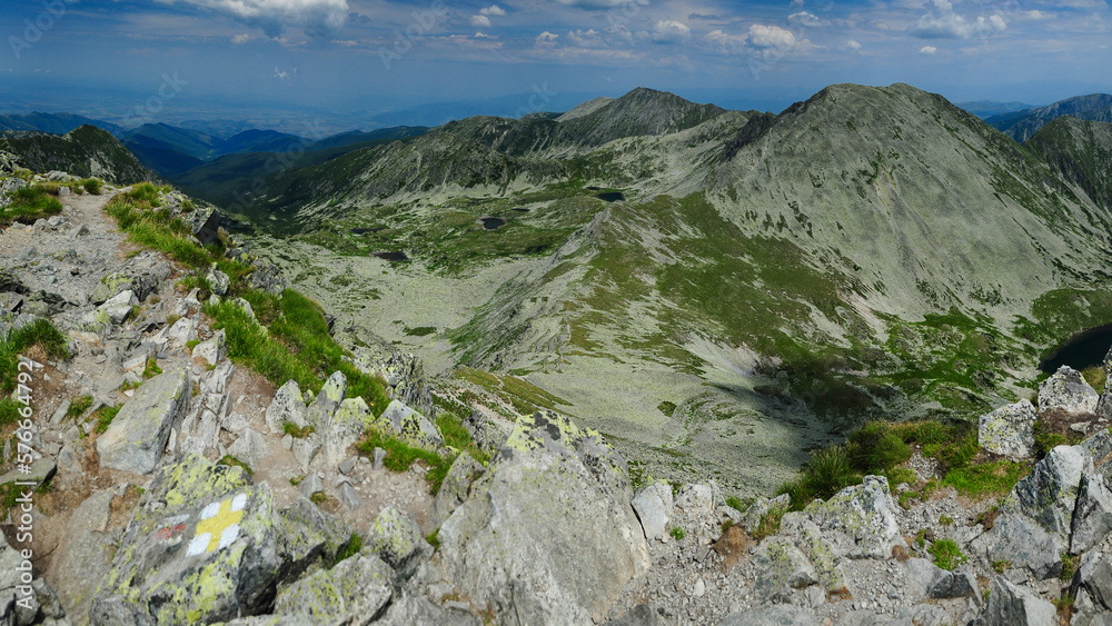 Panorama above the high summits of Retezat Mountains and the glacier lakes and cauldrons beneath them. High altitude landscape with rocky mountains and alpine pastures. Carpathia, Romania.