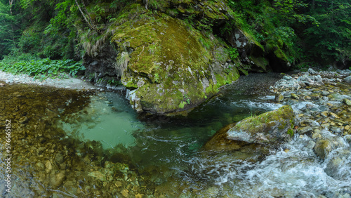 Canvas-taulu A river flowing rapidly along a stony watercourse
