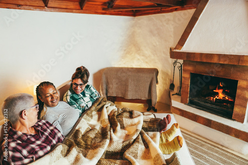 Multiracial friends having fun in front of cozy fireplace at home - Soft focus on african woman face