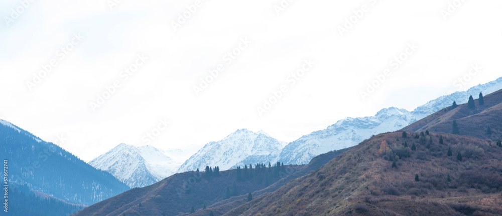 Panorama of a mountain landscape in northern China with snow-capped mountains. Foggy autumn day with first snow in Qitai county Xinjiang Uygur Autonomous Region, China.