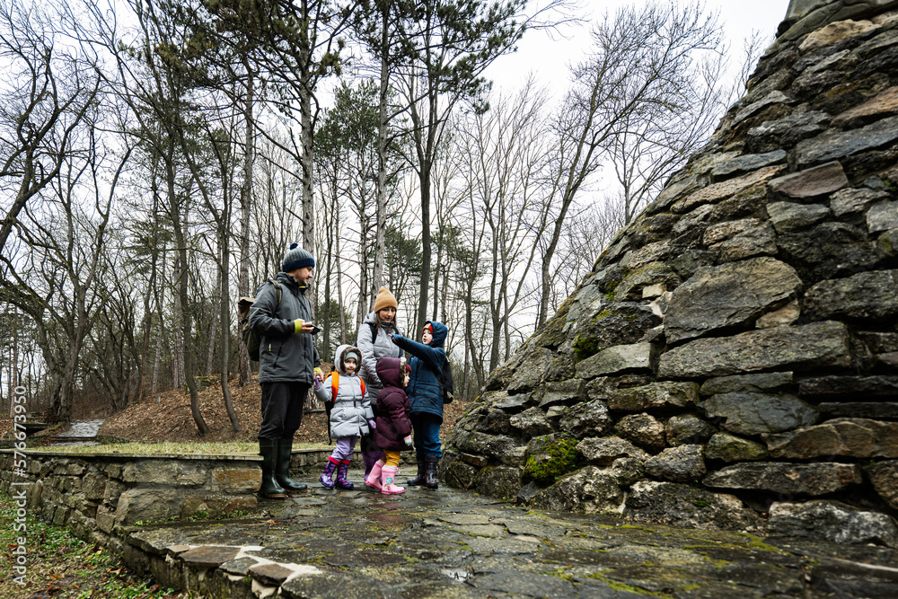 Obraz premium Family tourist with three children, stand near stone monument in forest.